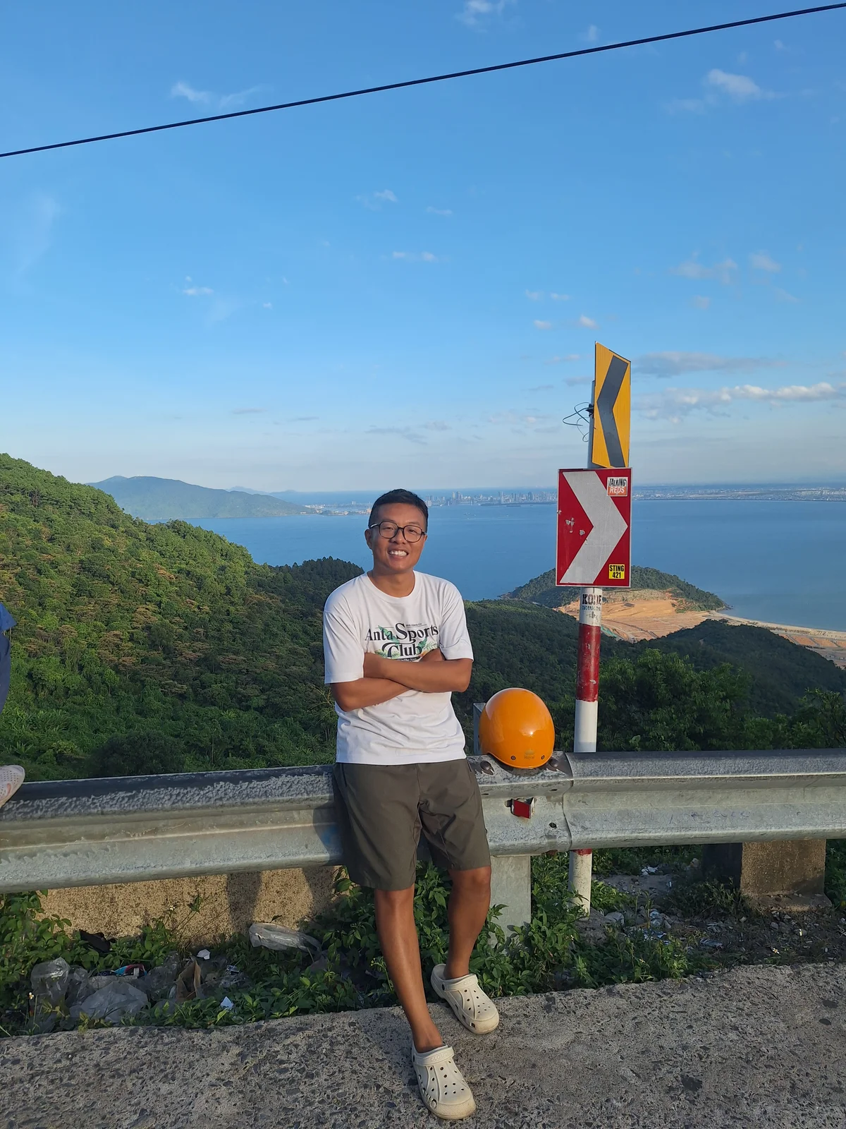 Edward leaning on a road barrier on Hai Van Pass, overlooking Da Nang bay.